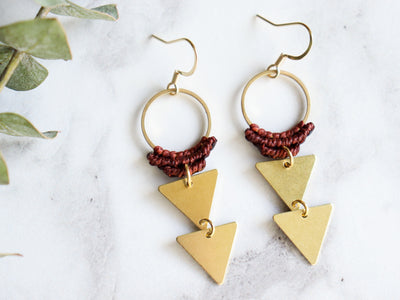 Pair of Double triangle drop macrame earrings in red and golden color in white background.