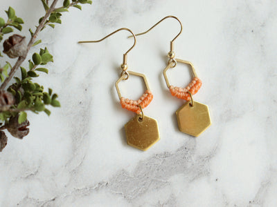Closeup Mini hexagon style macrame earrings in orange and golden color. 